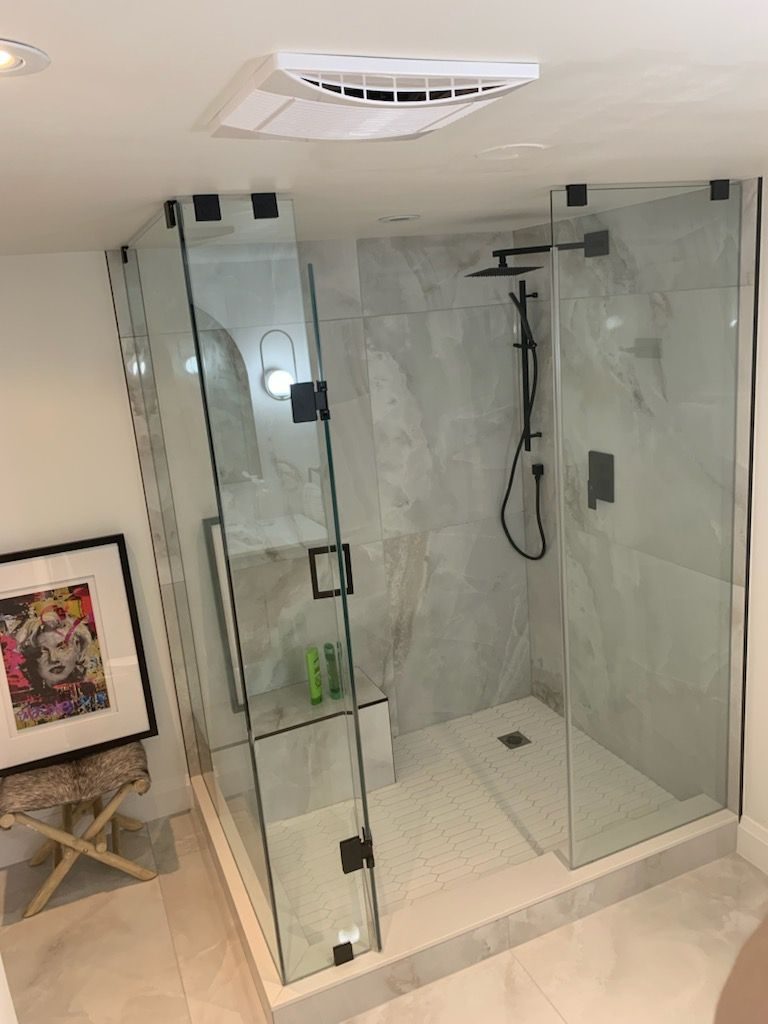 Bathroom with a glass walk-in shower, marble tile and black fixtures