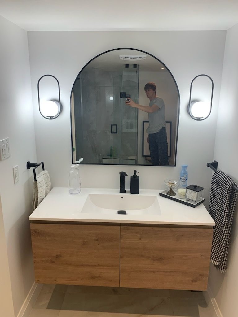 Bathroom with a floating wood vanity and an arched mirror