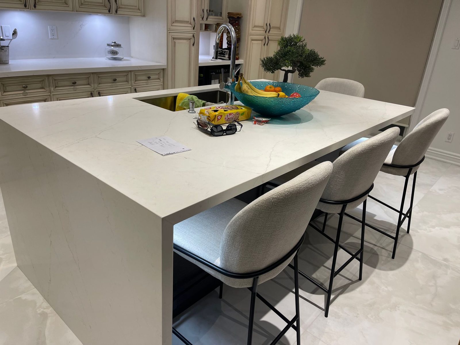 Custom kitchen island photographed at an angle with a waterfall-edge counter and bar stools